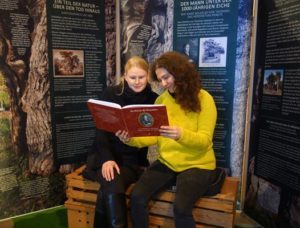 Museumsmitarbeiterinnen Franziska Huberty und Marlene Hofmann mit dem Buch über Hans Wilhelm von Thümmel in der Sonderschau. (Foto: Burg Posterstein)