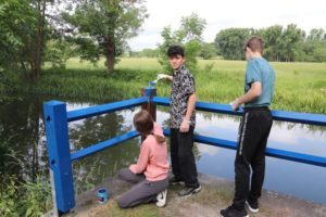 v. l. n. r.: Amelie, Noralie und Kiril aus der 8. Klasse von der Regelschule „Am Eichberg“ streichen in Großstöbnitz an der Papiermühle die Geländer mit frischer Farbe. (Foto: Landratsamt ABG)