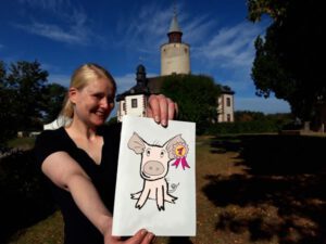 Franziska Huberty mit einem Bild des gesuchten Ferkels Schweinhilde (Foto: Burg Posterstein)