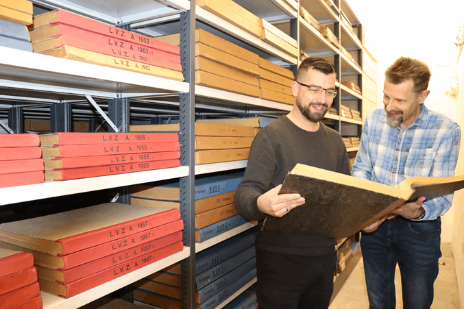 Mike Tänzler (l.) und Daniel Tietz recherchieren in alten Zeitungsbänden. (Foto: Landratsamt)